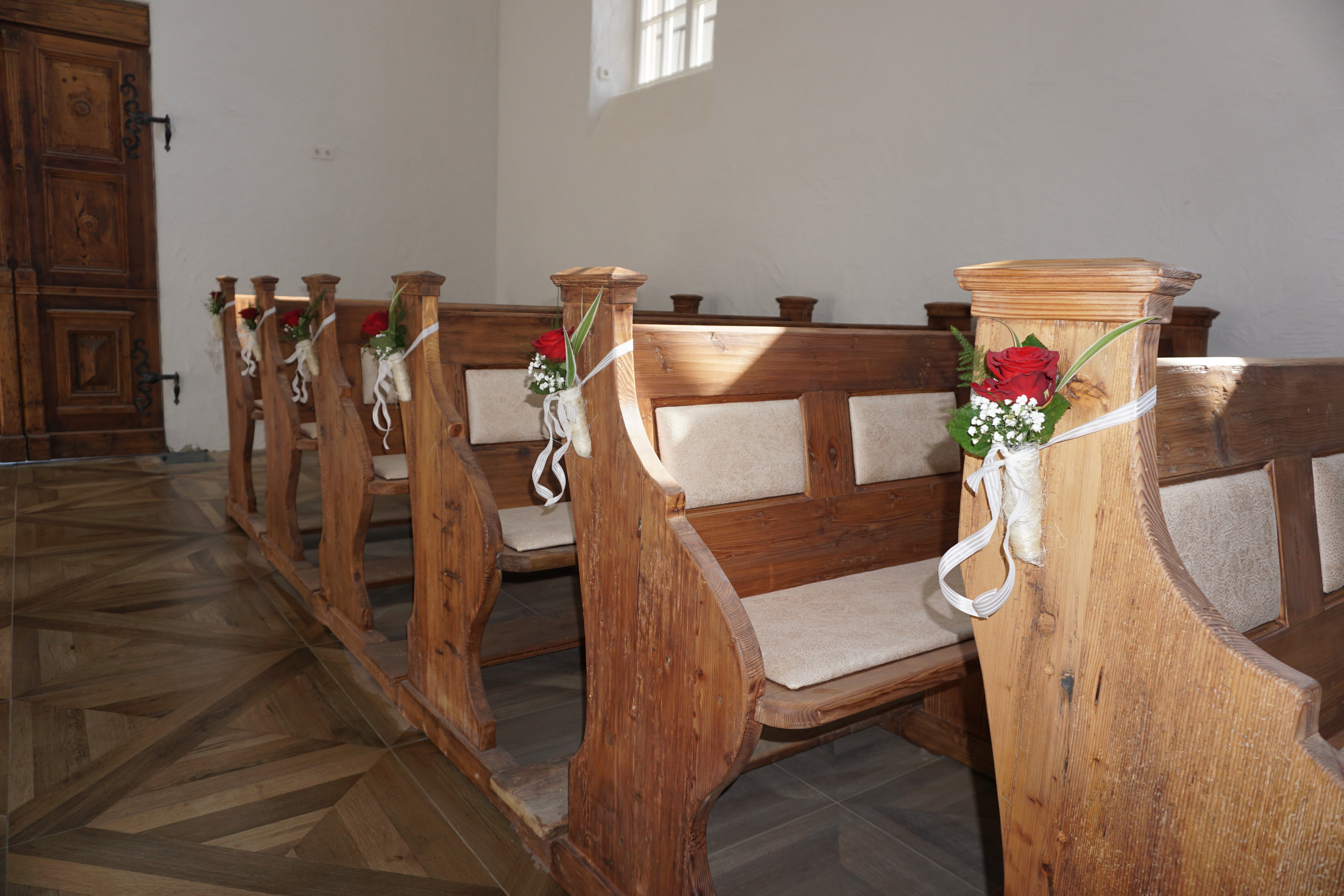 Geschmückte Kirchenbänke für die Trauung in der Hochzeitskapelle