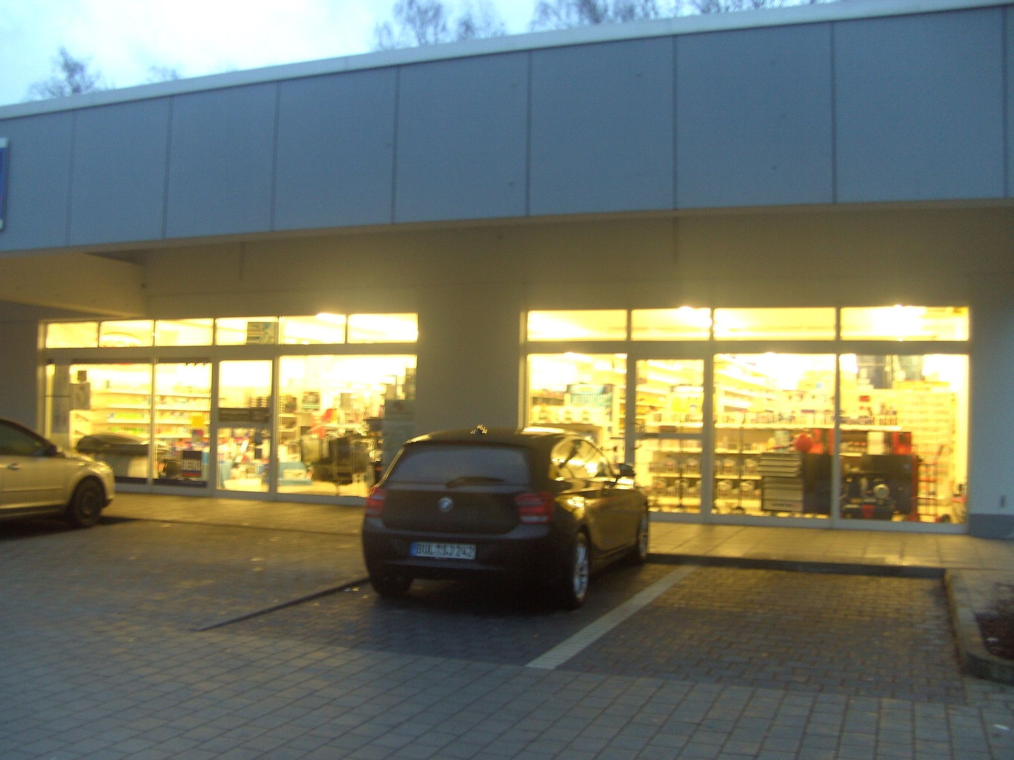 Schaufenster mit Eingangsbereich und Parkplatz