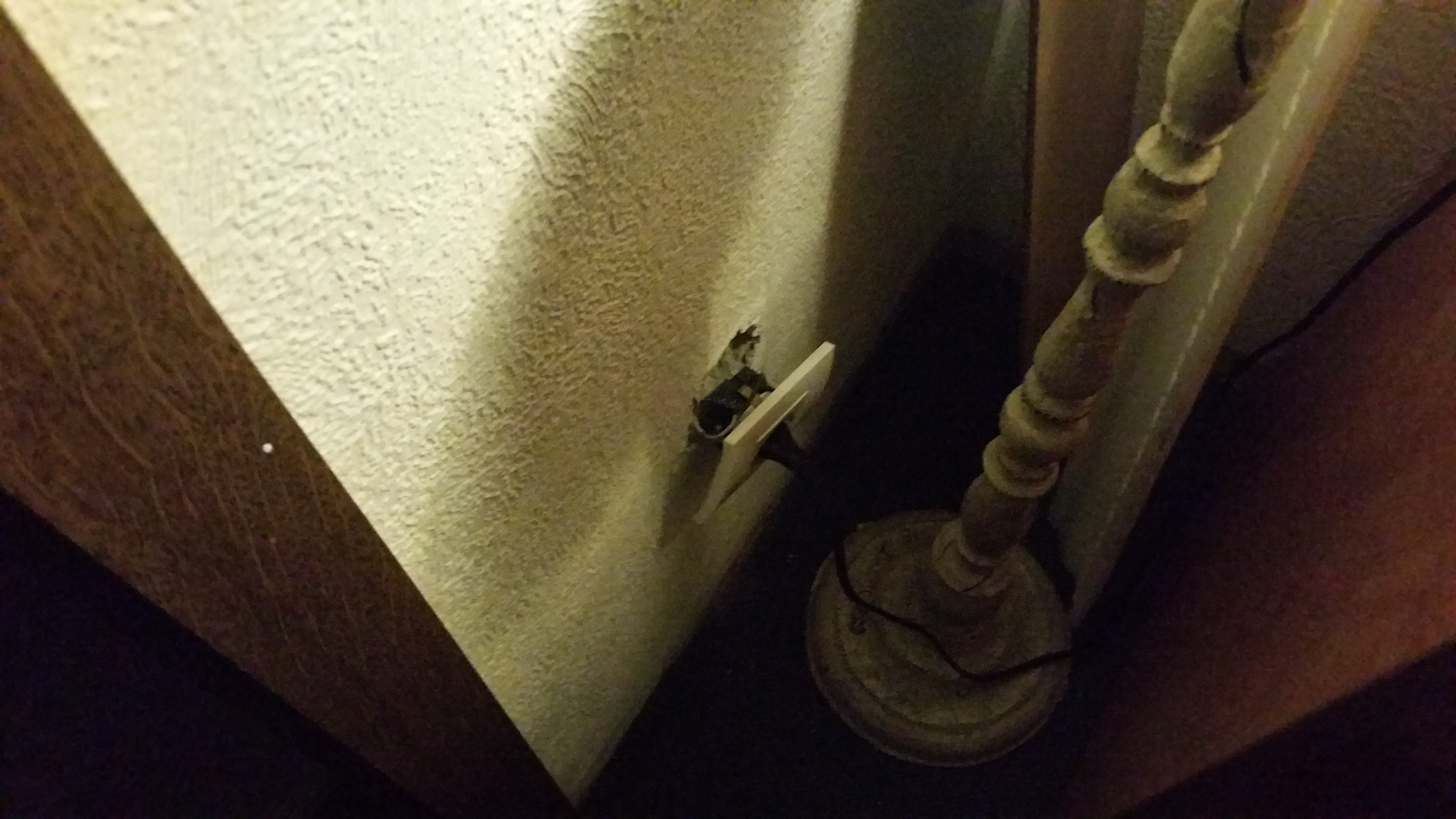 Steckdose aus der Wand herausgerissen, daran angeschlossen eine Stehlampe