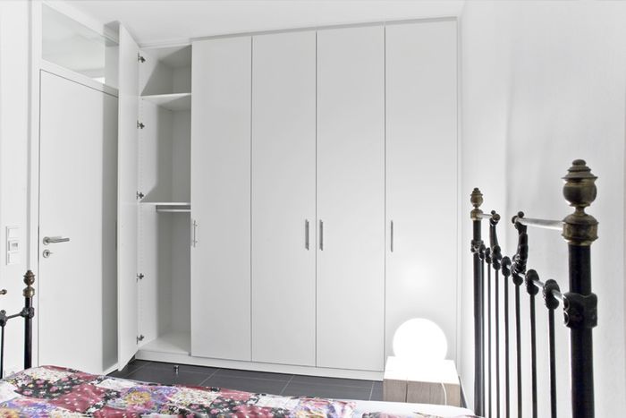 Einbaukleiderschrank im Gästezimmer. Genau eingepasst in den zur Verfügung stehende Platz hinter der Tür, bietet der Einbauschrank viel Platz für Kleidung und andere Dinge. Hinter den Drehtüren verbergen sich viele Kleiderstangen und Einlegeböden.