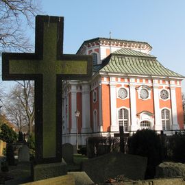 Schlosskirche und Grabkreuz aus Stein.