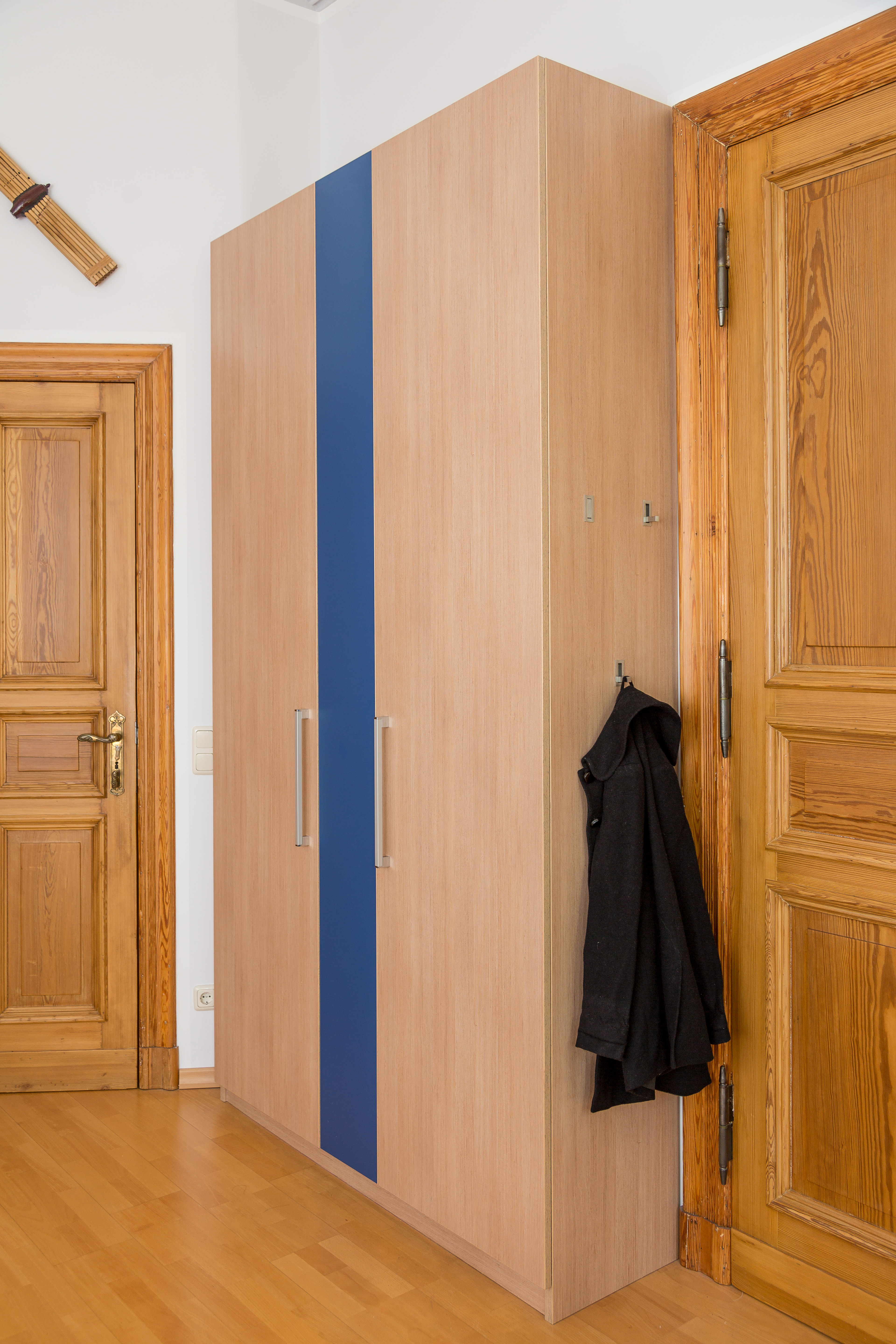 Kleiderschrank mit drei Türen - die grifflose, 
mittlere sieht aus wie eine Festblende - gehört zu einem vierteiligen Ensemble in einem Schlafzimmer