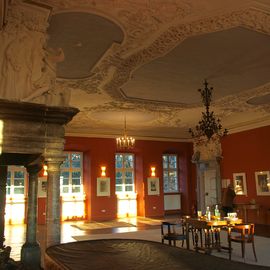 Der große Kaminsaal mit barocker Stuckdecke