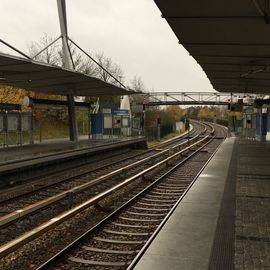 Bahnsteig mit Fußgängerbrücke im Hintergrund