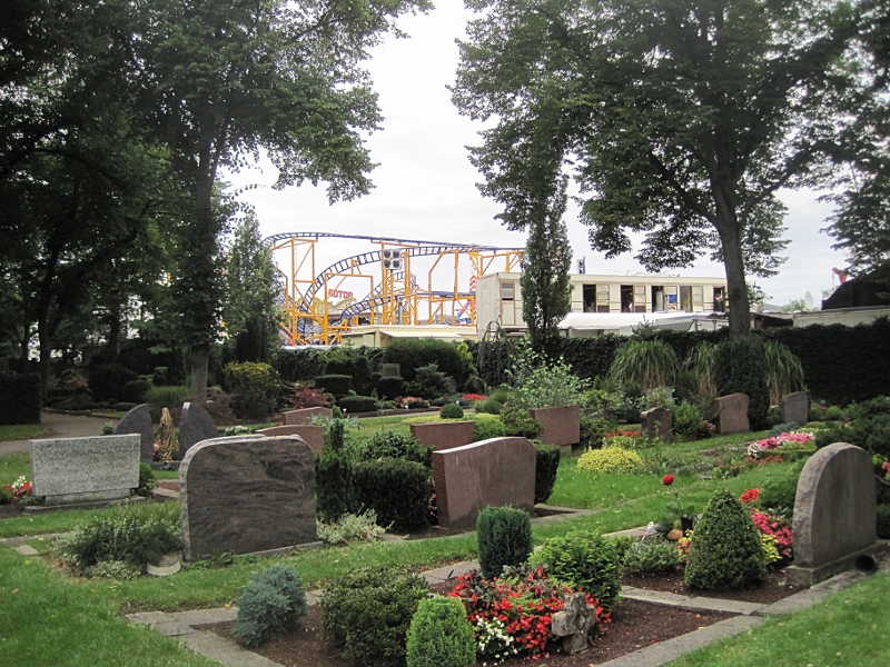 Der Friedhof der Kirche. Im Hintergrund sieht man die Fahrgeschäfte der Cranger Kirmes