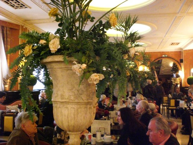große Blumenvasen mit (künstlichen?) Blumensträußen zieren den hinteren Teil des Cafés
