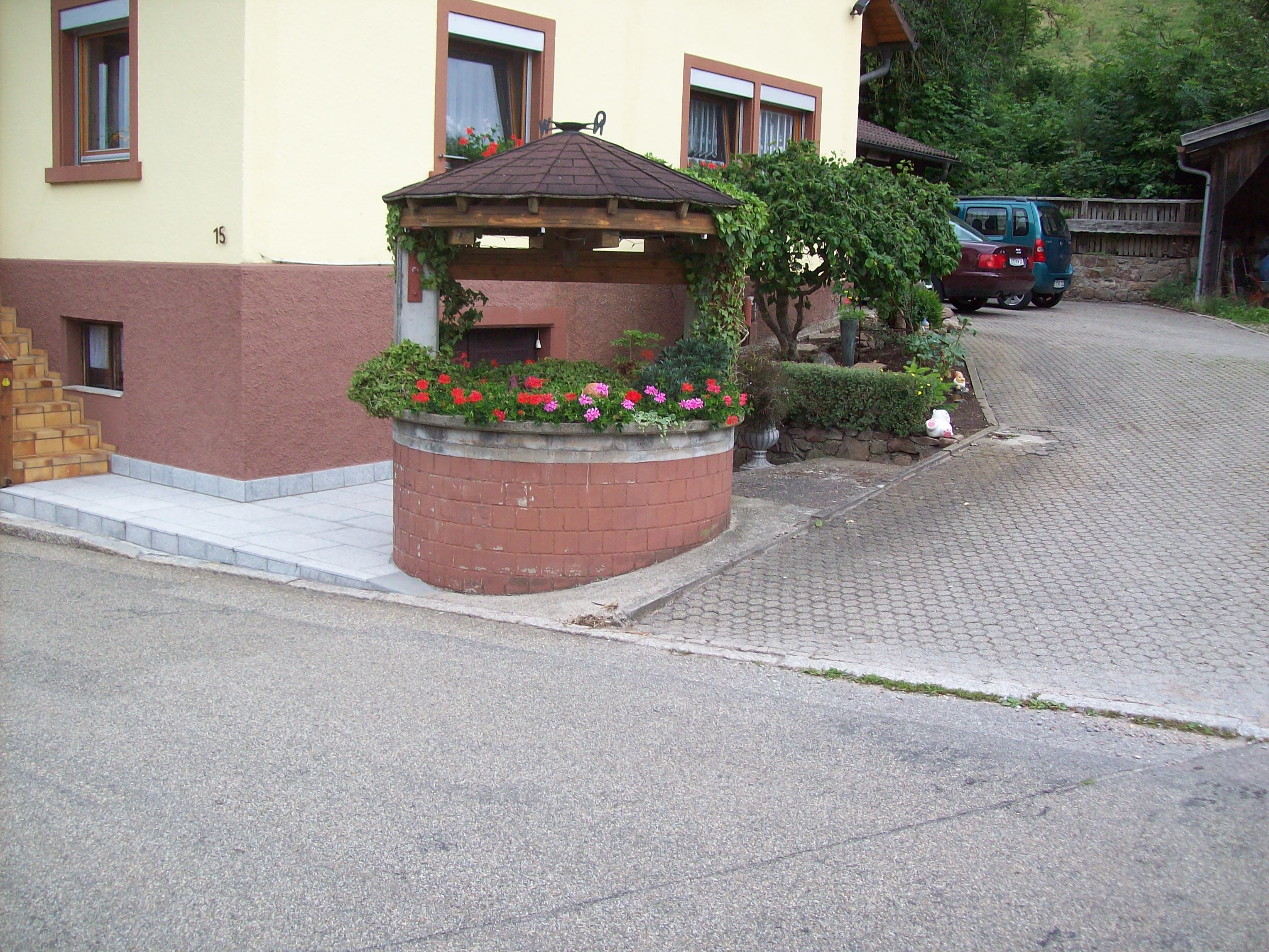 In unmittelbarer Nachbarschaft gelegen, ein mit Blumen geschmückter alter Brunnen