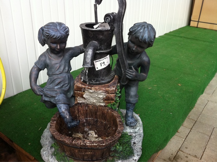 Spielende Kinder an der Wasserpumpe