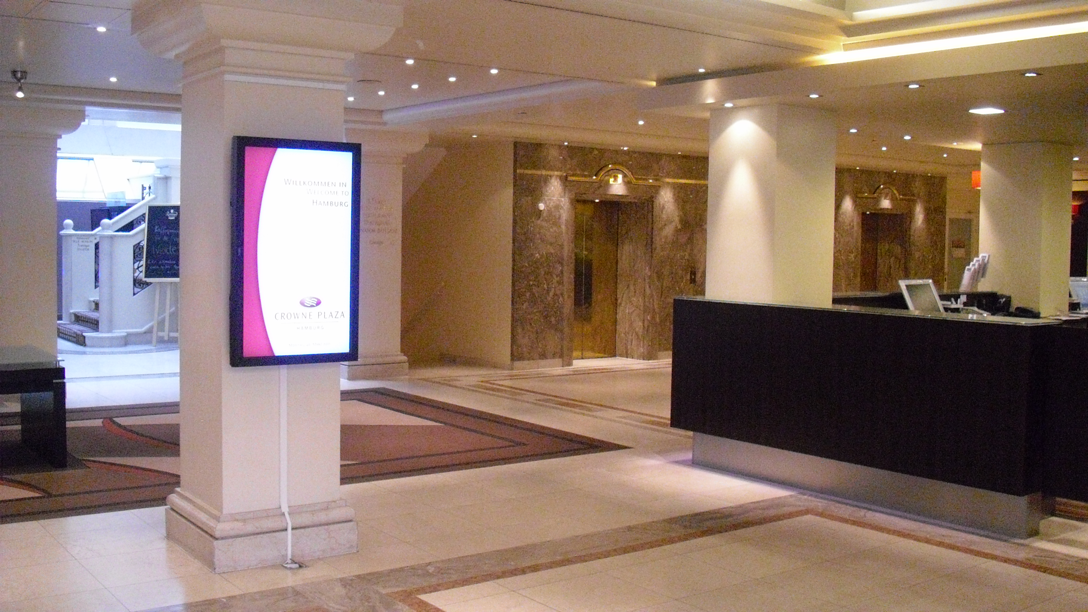Eingangsbereich mit Rezeption, digitaler Anzeige und den Aufzügen