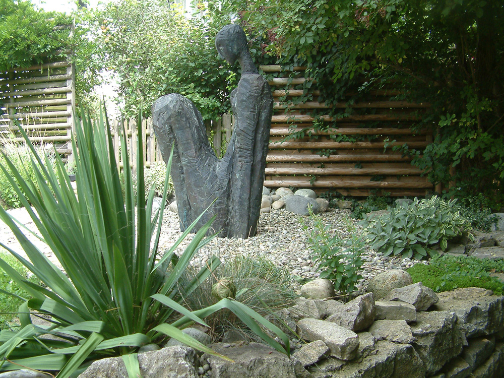 eine Steinstatue als Blickfang im professionell gestalteten Garten, gestaltet von Ralf Kretzer Naturnahe Gartengestaltung Würzburg und Umgebung