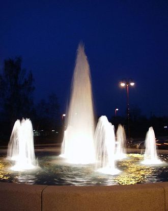 Blick auf den Brunnen am Kreisverkehr vom Hotel aus bei Nacht.