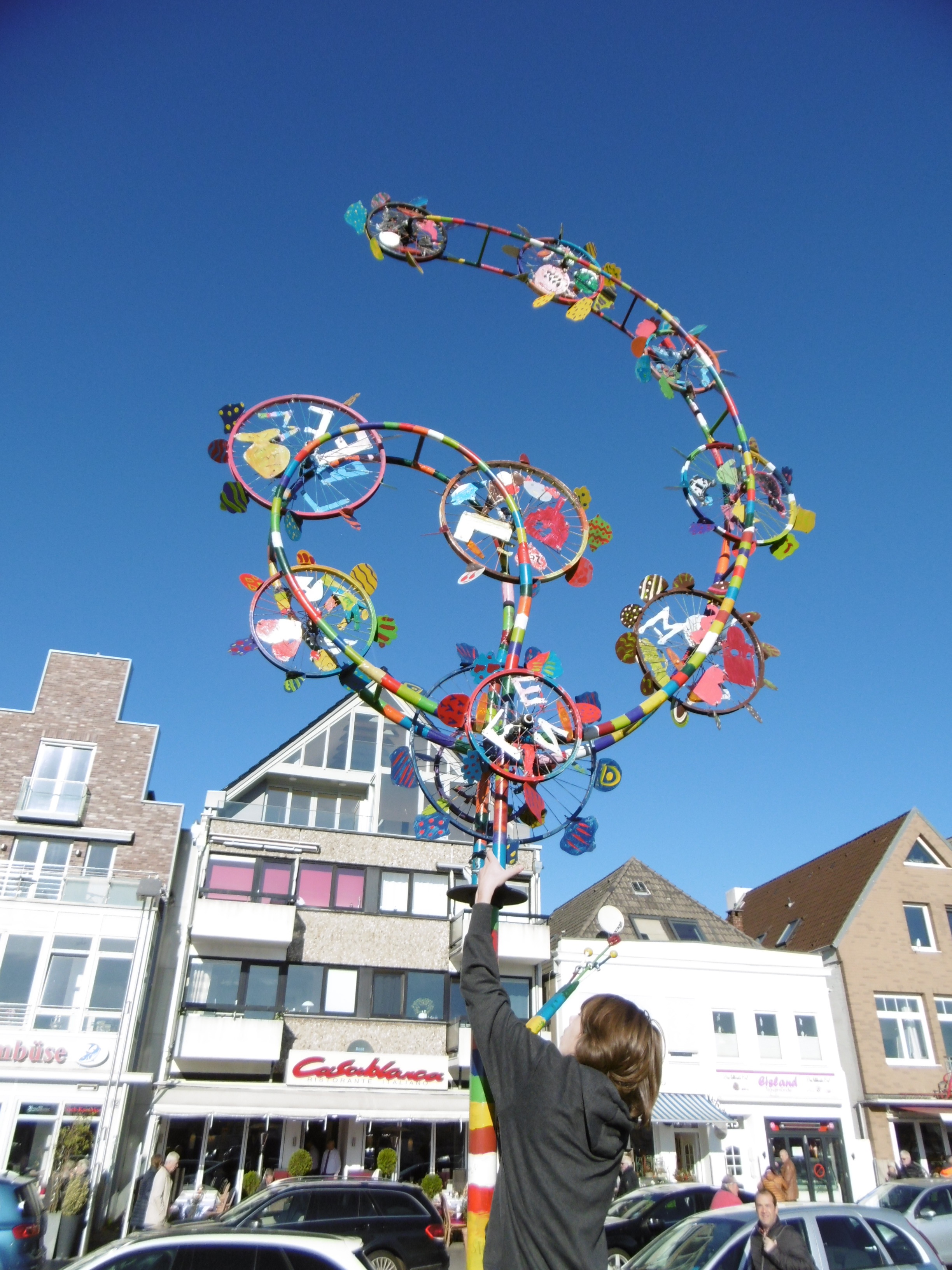 Wind Art Travemünde, vor
dem Casablanca das kinetische Kunstwerk Windblüte, wahrscheinlich sind die farbigen Windräder von de ebefalls farbefrohen Pizzen inspiriert worden. Schon leichter Wind lässt das Kunstwerk in Bewegung geraten. Ein Kunstprojekt Siakkou-Flodin mit den Schüler der Stadtschule
