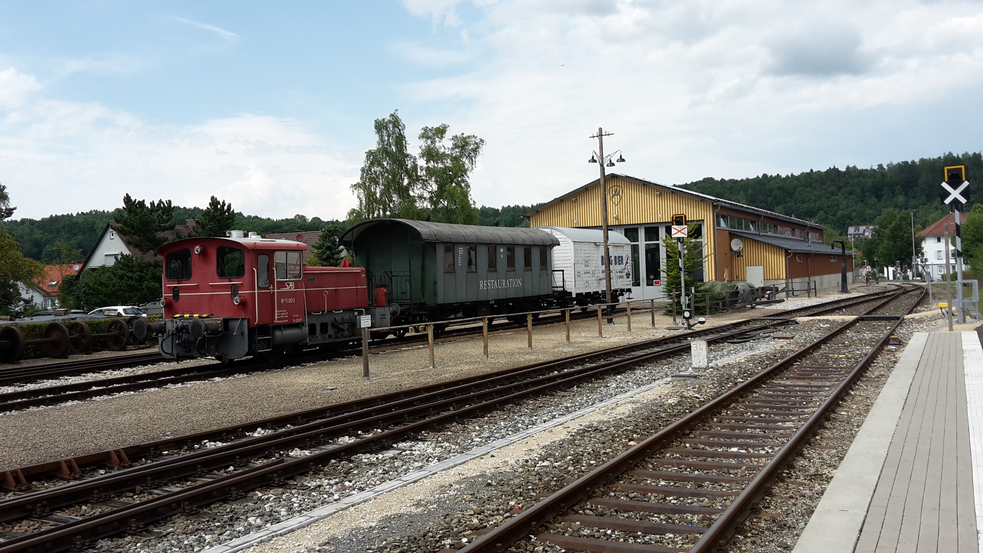 Der Lokschuppen der Schw&auml;bischen Alb-Bahn in M&uuml;nsingen mit  davor stehender Garnitur.