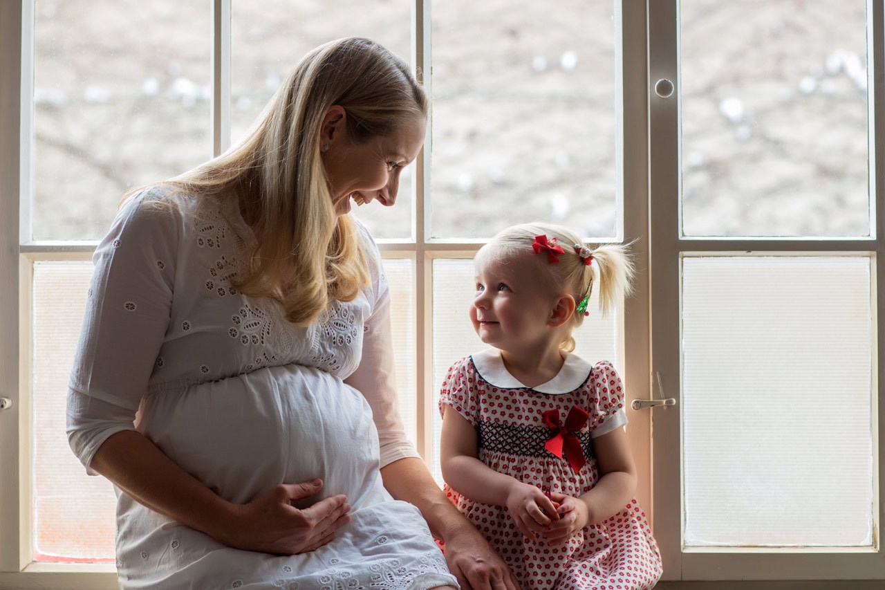 Schwangere mit Tochter vor Fenster