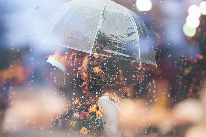 Brautpaar mit Schirm im Regen