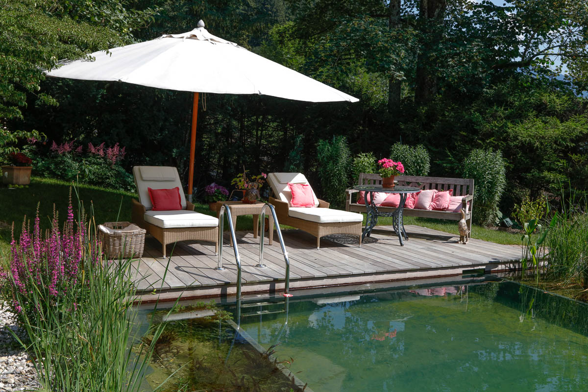 Kundengarten von Fuchs baut Gärten. Holzterrasse am Swimming Pond (Teich), wunderbarer Platz zum entspannen und den Blick in den Garten zu genießen.