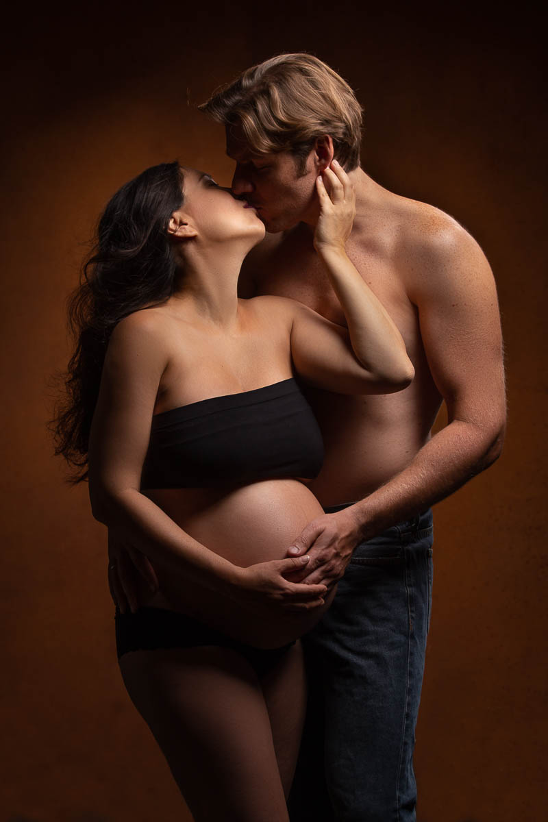 Werdende Eltern küssen sich bei einem Babybauch-Fotoshooting im Fotostudio Farbtonwerk