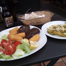 Bifteki mit Kroketten, Salat. Gegrillte Peperoni in Knoblauch. Hausgemachtes Brot und ein Schulli