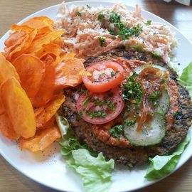 XXL-Sunburger mit frischem rohk&ouml;stlichem Ketchup, marinierten Gurken und gebratenen Zwiebeln; dazu ein Cole Slaw Salat (Wei&szlig;kohl und Karotten mit CashewMayo-Dressing) und S&uuml;&szlig;kartoffel-Chips