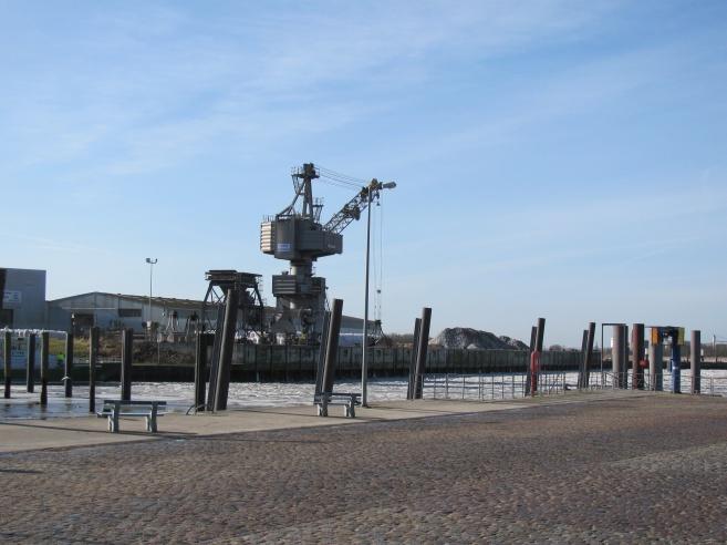 Ent- und Verladekran vor der Hafenschleuse, links Anlegestelle für das Zollboot