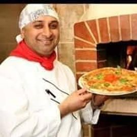 Inhaber Kuldeep Gurha Singh serviert eine leckere Pizza
