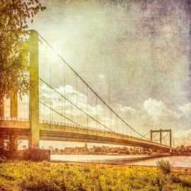 Ein Bild aus der Serie Köln ANNO. Hier ist besonders malerisch die Rodenkirchener Brücke zu sehen. Als Fine Art Print auf Alu Dibond oder gedruckt auf Hahnemühle Fineart-Papier. Mit Rhien, viel Himmel und Sonne.