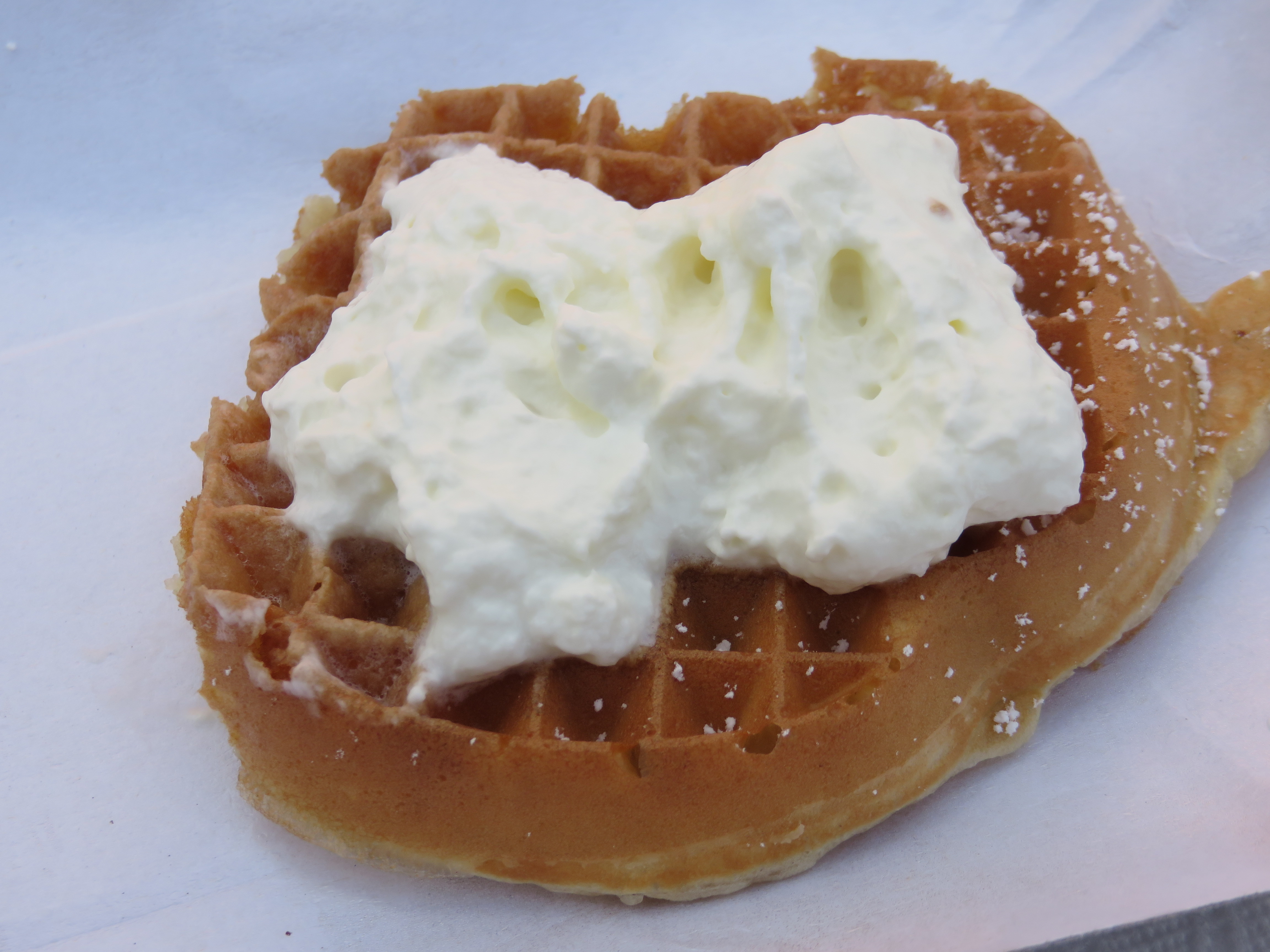 Ein Viertel einer Waffel mit Puderzucker und Sahne