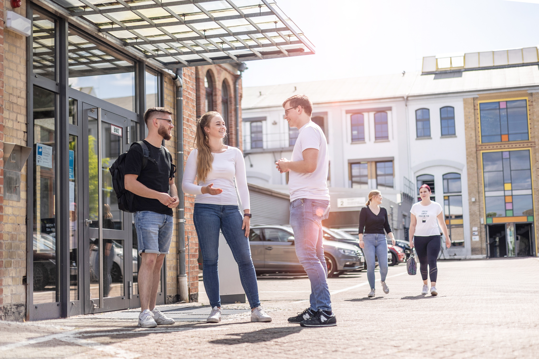 Schüler stehen vor dem Haupteingang von TEUTLOFF und unterhalten sich fröhlich.