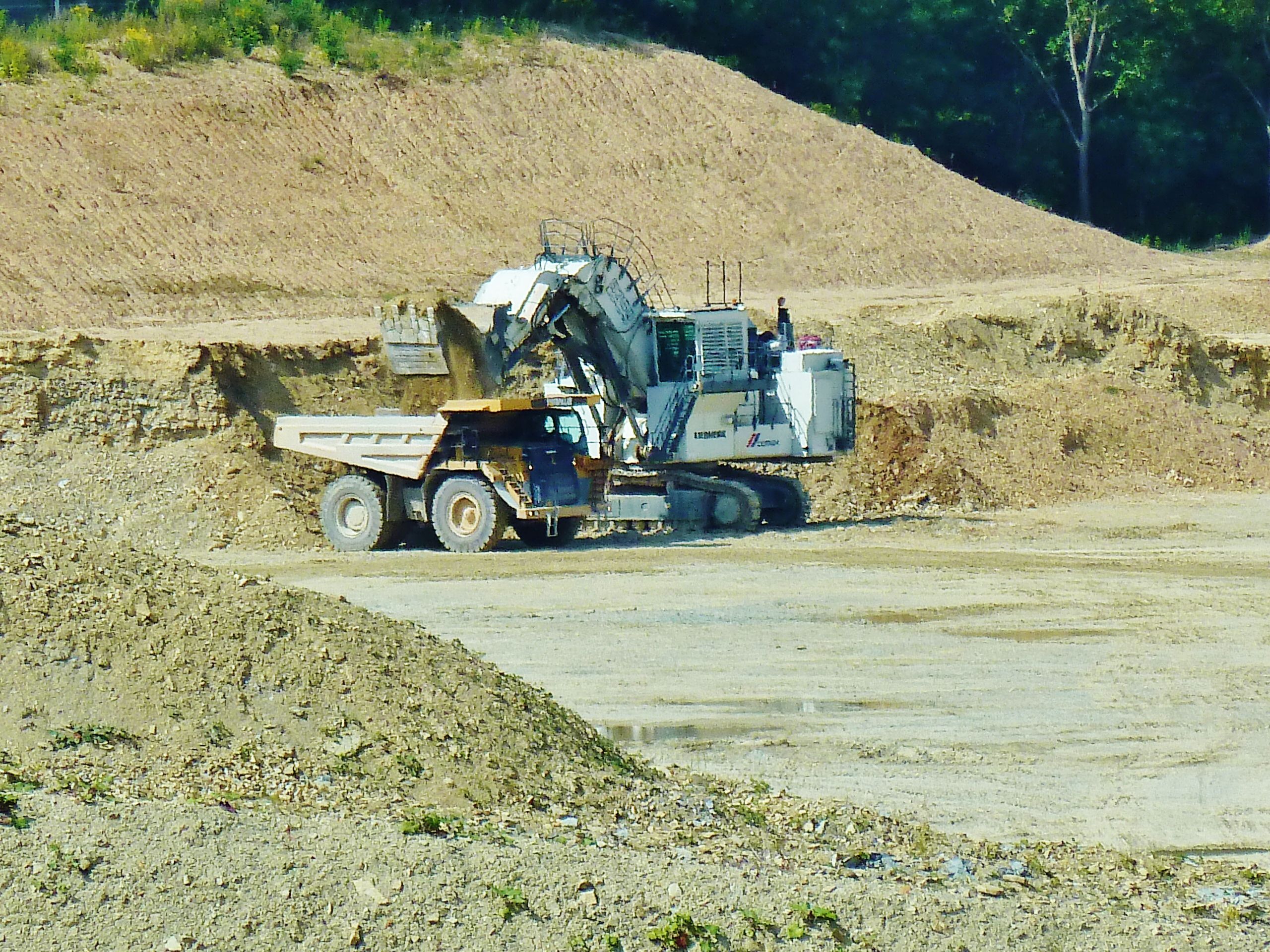 hier wird der gewaltige LKW gerade vom Bagger mit Abraum beladen.