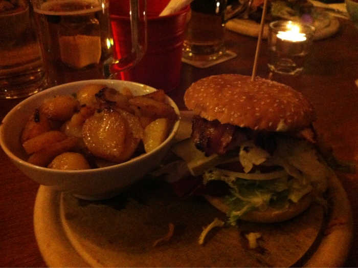 "Eva's Burger" (Hähnchenfilet, Bacon, Eisbergsalat, Tomate, Remoulade) mit Bratkartoffeln.