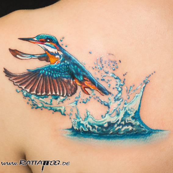 Eisvogel fliegt aus dem Wasser. Tattoo auf der Schulter aus dem Rattattoo Tattoostudio in Freiburg.