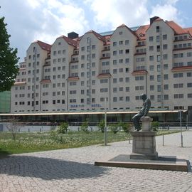 Maritim Hotel Dresden, aufgenommen von der Elbpromenade, im Vordergrund steht ein Dostojewskij-Denkmal