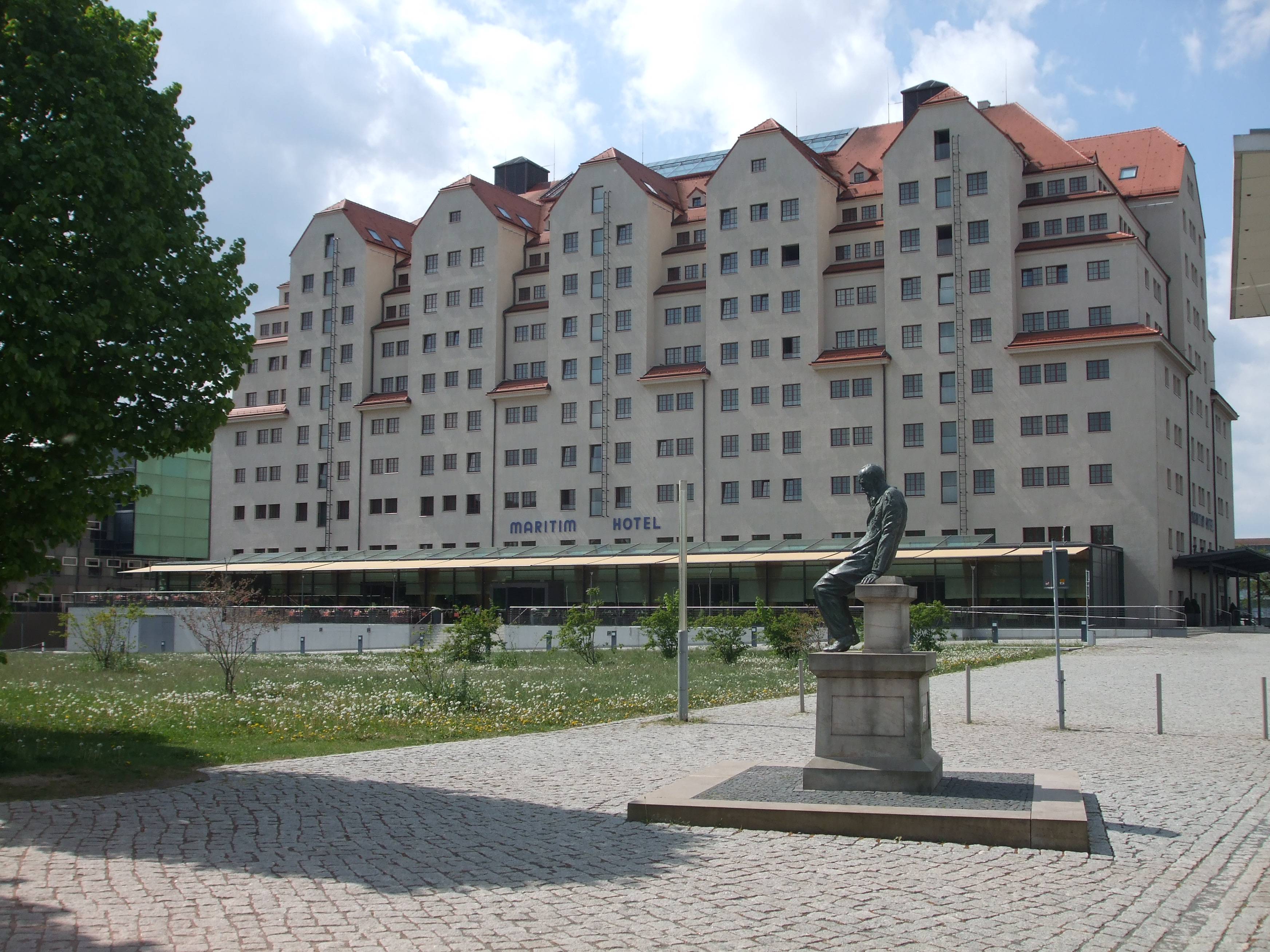 Maritim Hotel Dresden, aufgenommen von der Elbpromenade, im Vordergrund steht ein Dostojewskij-Denkmal