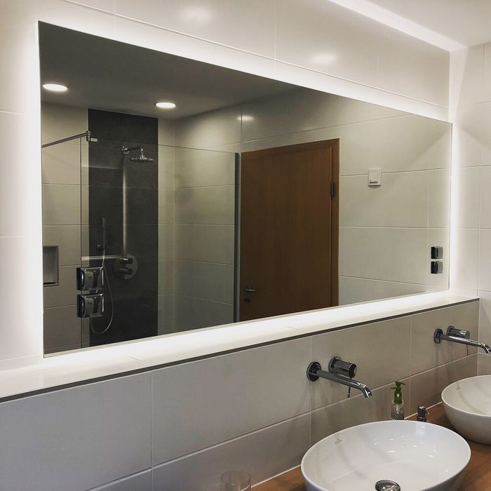LED Badspiegel mit Ambientebeleuchtung in neutralweiß und aufgesetzten Steckdosen in der Spiegelfläche. Gefertigt im Individualmaß nach Kundenwunsch.